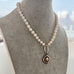 Pearl and antique watch fob necklace on a mannequin bust.