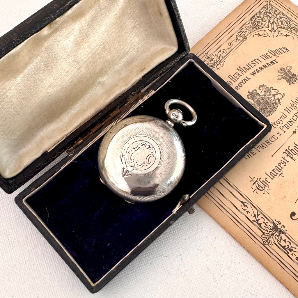 Silver antique sovereign holder in an open box with a document on a white surface