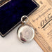 Silver antique sovereign holder in an open box with a document on a white surface