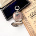 Silver antique sovereign holder in an open box with a document on a white surface