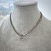 Silver chain necklace on a mannequin bust with a blurred cityscape background
