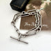 Antique silver trombone chain bracelet on a white surface with a vintage-style card in the background.