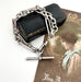 Antique silver trombone chain bracelet on a white surface with a vintage-style card in the background.