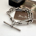 Antique silver trombone chain bracelet on a white surface with a vintage-style card in the background.