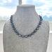 Necklace with dark pearls on a gray mannequin against a window background