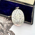 Antique Victorian era silver locket with an engraving of an urn and an old jewellery box
