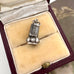 An antique silver wax seal fob charm pendant with engraved leaf and chevron patterns, displayed inside an open vintage burgundy velvet jewelry box with cream velvet lining.