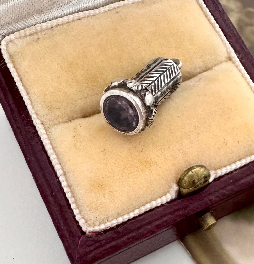 An antique silver wax seal fob with a round dark purple cabochon gemstone, displayed inside an open vintage-style burgundy velvet ring box.