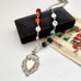 Necklace with multicolored beads and antique silver watch fob on a white surface and jewelry box and floral card.