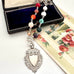 Necklace with multicolored beads and an antique silver watch fob  on a floral-themed card.