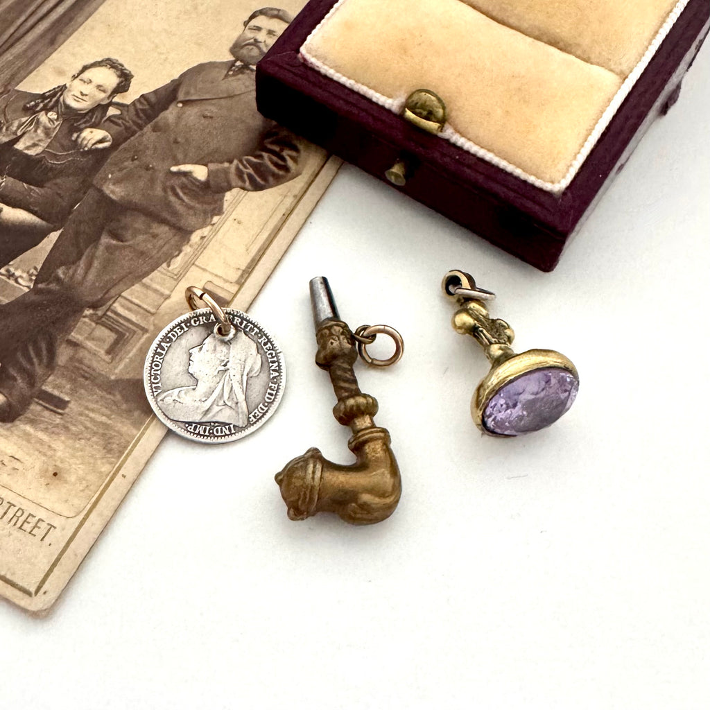 Three vintage-style pendants on a white surface with an old photograph and jewelry box.