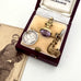 Antique jewelry set with a pendant and brooch in an open jewelry box, next to a vintage photograph.