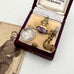 Antique jewelry set with a pendant and brooch in an open jewelry box, next to a vintage photograph.