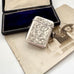 Antique 1911 William Hair Haseler silver vesta case with intricate designs on a vintage photo and box