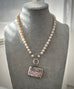White pearl necklace with an antique silver vesta case pendant on a grey mannequin
