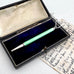 Art Deco silver and guilloche enamel propelling pencil, displayed inside an open vintage black presentation box with a dark blue velvet lining, next to an antique handwritten letter.