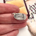 Silver pendant on a finger with a decorative background