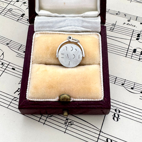 Silver vintage spinning I Love You charm in a jewelry box on sheet music