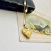 Gold heart-shaped locket necklace on an old box with floral and fan postcard