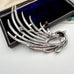 Back of a silver tone bird brooch in a box on a white surface