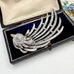 Decorative brooch with a bird design on a black background in an open jewelry box.