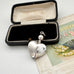 Silver heart-shaped perfume bottle pendant in an open black box with a vintage card in the background
