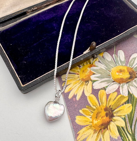 Necklace with a heart-shaped pearl charm on a floral card