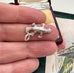 Silver platypus charm/pendant held between fingers with a decorative box in the background