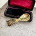 Decorative Silver Sami spoon with intricate designs in an open velvet box on a textured surface.