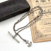 Antique silver albertina chain necklace with an anchor pendant on a vintage box and antique advertising material. 
