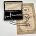 Antique silver albertina chain necklace with an anchor pendant on a vintage box and antique advertising material. 
