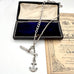 Antique silver albertina chain necklace with an anchor pendant on a vintage box and antique advertising material. 