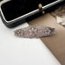 Victorian silver floral sweetheart brooch displayed inside an open black velvet jewelry box with a cream lining, with a vintage portrait card partially visible underneath.