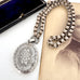Victorian silver belcher chain with a decorative locket on a white surface next to an old photograph.