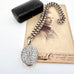 Victorian silver belcher chain with a decorative locket on a white surface next to an old photograph.