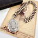 Victorian silver belcher chain with a decorative locket on a white surface next to an old photograph.