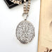 Victorian silver locket with intricate designs on a white surface