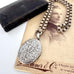 Victorian silver belcher chain with a decorative locket on a white surface next to an old photograph.