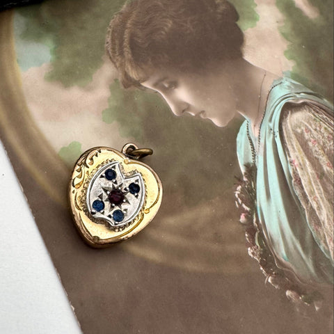 Vintage heart-shaped locket with blue stones on an old photo