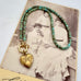 A vintage Carl Art gold heart-shaped locket pendant and a beaded turquoise-blue chain, displayed  on a vintage printed card.