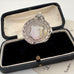 Silver medallion with a shield design in an open black velvet box.