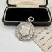Silver medal with wreath design in an open box on a white surface