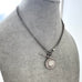 Silver chain necklace with a pendant on a gray mannequin bust