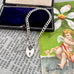 Silver chain bracelet with a lock charm on an old book page with an angel illustration.