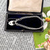 Silver bracelet with heart charm in an open jewelry box on a vintage-style magazine background.