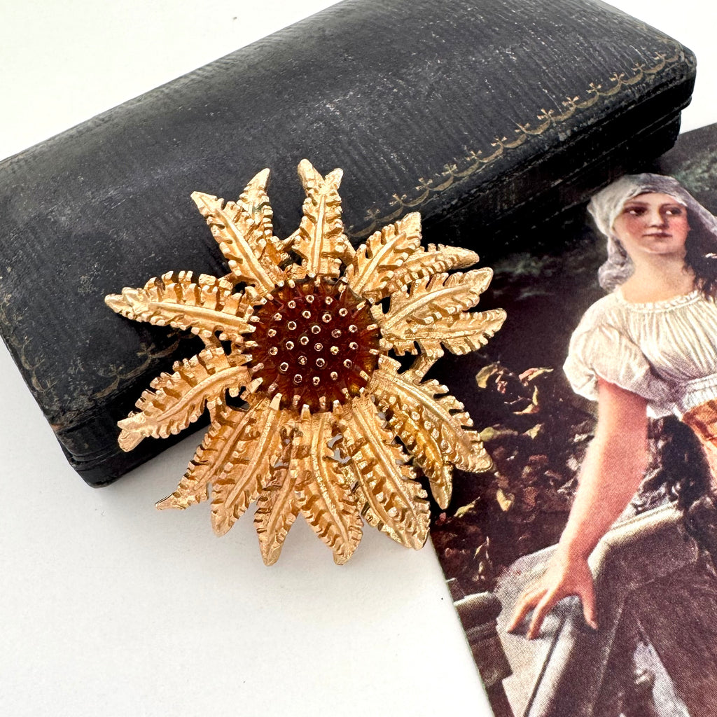 Vintage 1968 Sarah Coventry Cosmopolitan sunflower brooch on an old jewellery box and with an old postcard