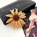 Vintage 1968 Sarah Coventry Cosmopolitan sunflower brooch on an old jewellery box and with an old postcard