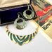 A gold and teal enamel jewelry set featuring a scalloped statement necklace and matching circular drop earrings, displayed with a velvet jewelry box and a vintage-style card.
