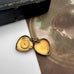 Vintage 9ct gold lined heart locket with gemstone on an old postcard