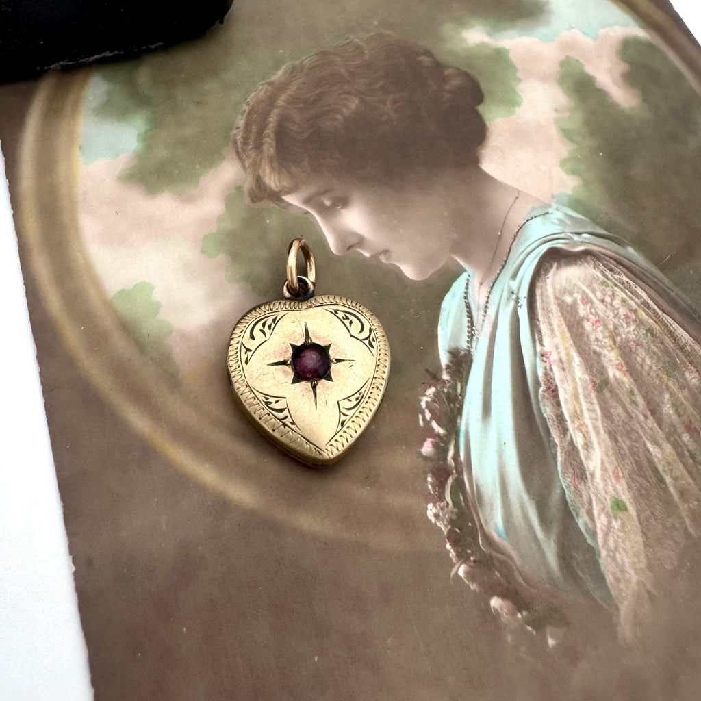 Vintage 9ct gold lined heart locket with gemstone on an old postcard